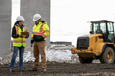 two workers with hard hats near construction equipment