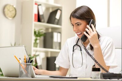 medical professional sitting at a desk while talking on the phone