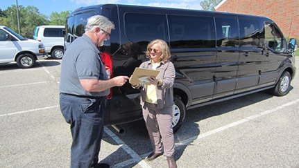 people standing next to black van, looking at clipboard