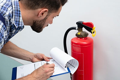 man inspecting fire extinguisher
