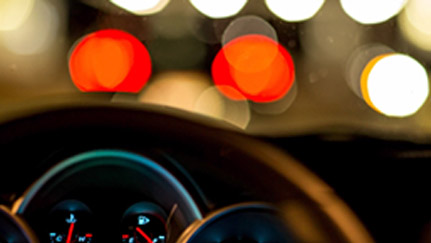 Steering wheel with blurry streetlights in the foreground